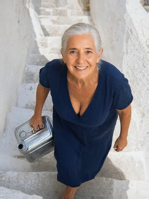 AI image of Popi climbing whitewashed stone steps with a large olive oil tin in one hand.